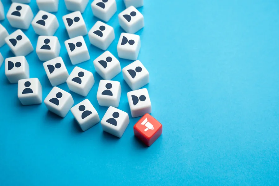 Scattered dice featuring people silhouettes with one red die at the top