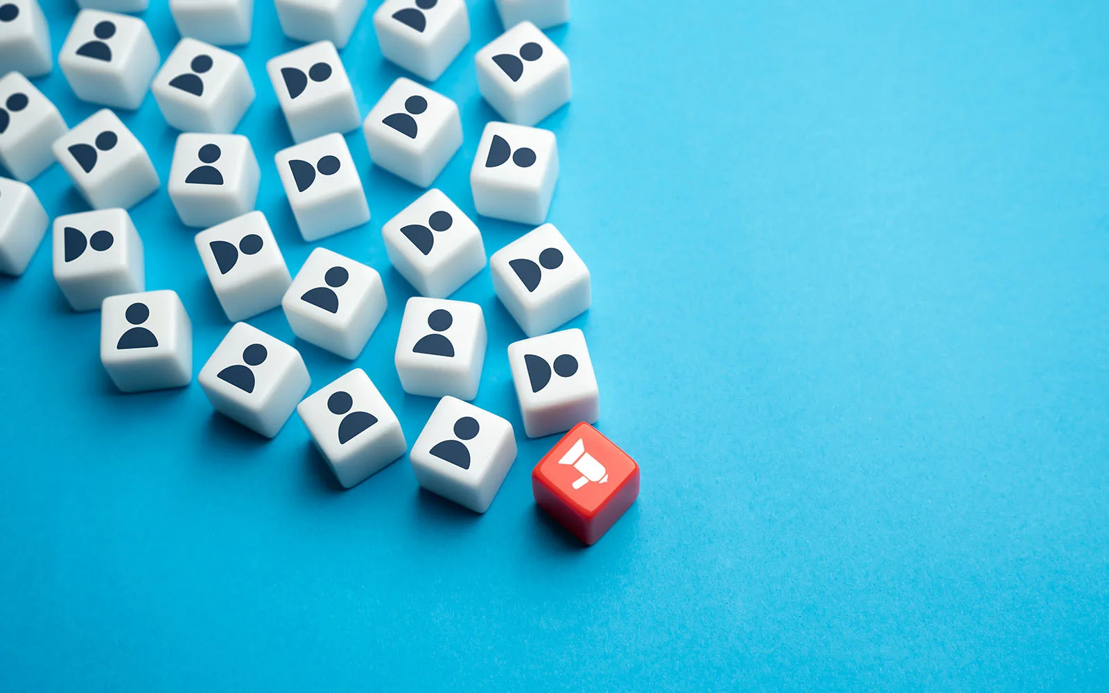Scattered dice featuring people silhouettes with one red die at the top