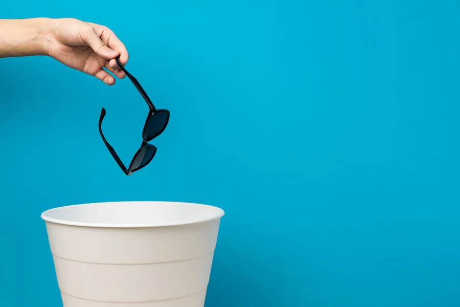 A person dropping sunglasses into a bucket