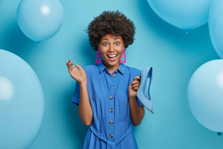 A woman in blue smiling and standing against a blue backdrop