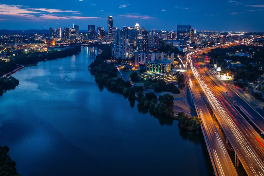 A view of the Austin, TX, skyline at night over Lady Bird Lake, near I-35