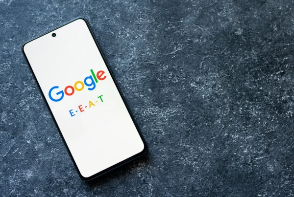 A white cell phone screen with colorful text spelling the words: Google E-E-A-T