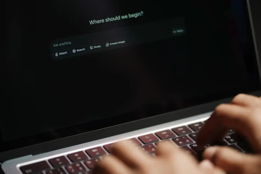 A closeup image of a person typing on a laptop screen displaying an AI system prompt box