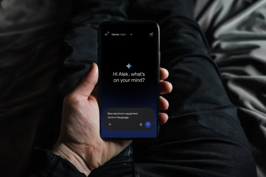 A man holding an iPhone displaying a welcome prompt from Google Gemini on the screen.